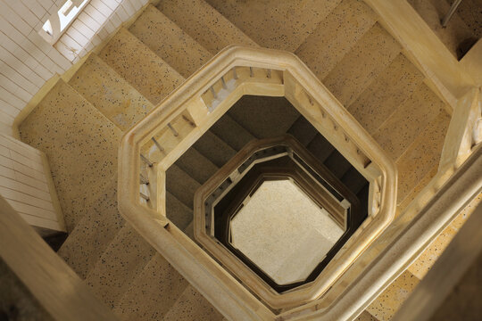 Top view abstract geometric perspective of a beige terrazzo spiral staircase looking down.