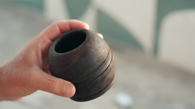 Man's hand holding a traditional wooden cup for drinking mate, a popular beverage from argentina, uruguay and paraguay