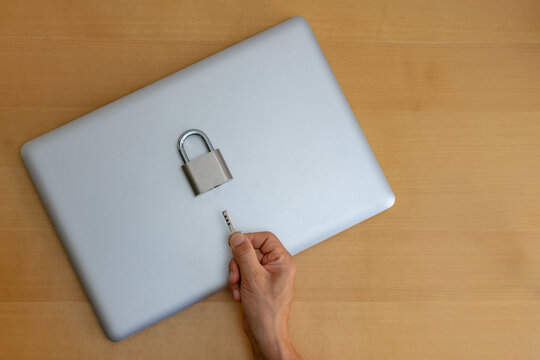 Top view of locked laptop with padlock and key on desk
