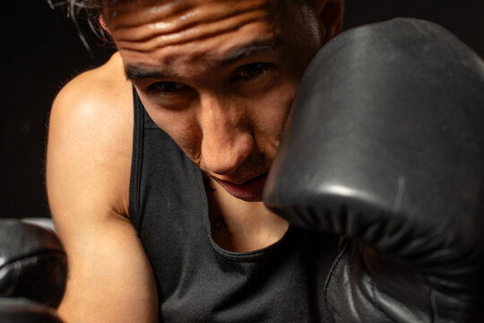 Close up Hispanic boxer protecting face with gloves during training