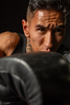 Close up Hispanic boxer with blurred glove in foreground during training
