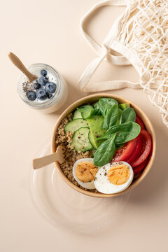 Healthy protein bowls with egg, quinoa, avocado, spinach, cucumber  in cardboard containers, served with chia seed yogurt and blueberries in glass jars 