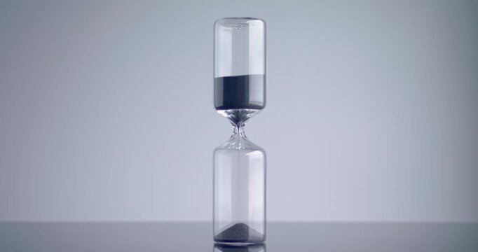 Time lapse of a modern design sand clock / hourglass on a grey background.