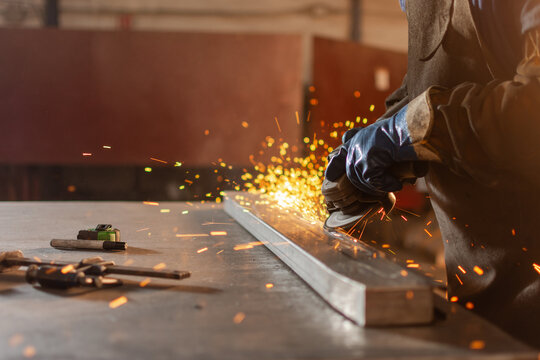 Close up of grinder disc cutting metal with sparks and gloved hands