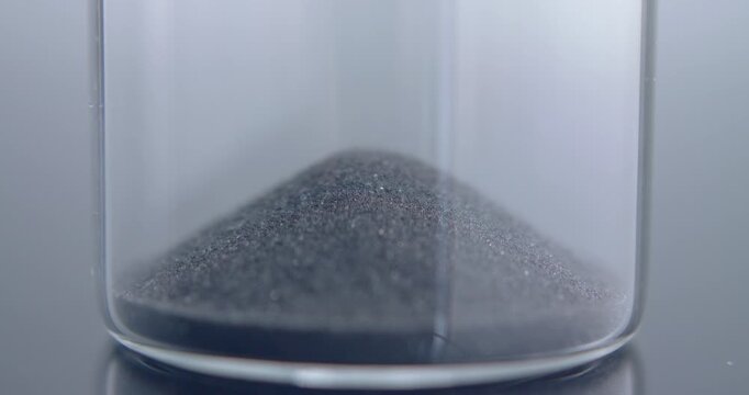 Close up macro shot of sand clock / hourglass sand pouring in slow motion.