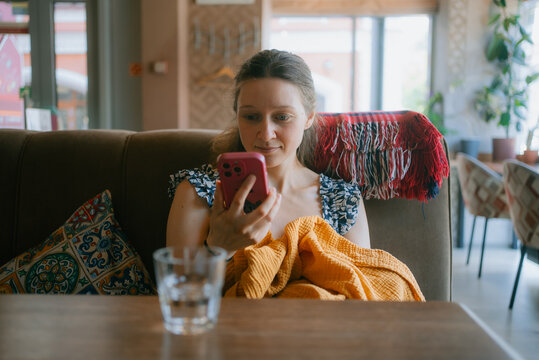 Mother juggling motherhood and social connection, multitasking with smartphone in a cozy cafe, enjoying a relaxing moment while staying connected, infant nearby