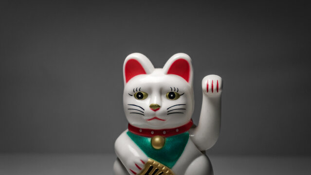 Chinese lucky cat Maneki Neko figurine waving its paw. Decorative fortune cat souvenir with different angles and close up views representing luck wealth and prosperity