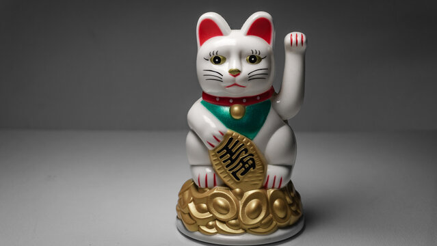 Chinese lucky cat Maneki Neko figurine waving its paw. Decorative fortune cat souvenir with different angles and close up views representing luck wealth and prosperity