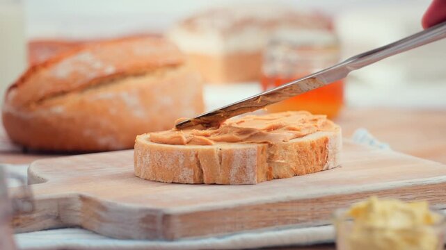 Peanut butter spread on fresh bread slice, homemade breakfast preparation, copy space