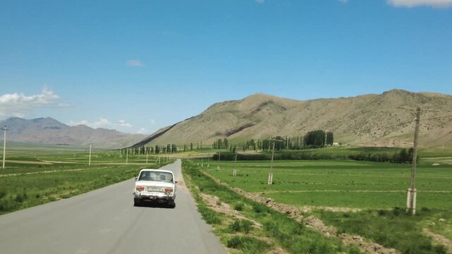 An old Soviet era Lada drives through the rural countryside in Kyrgyzstan.