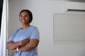 Fototapeta premium Adult African American woman posing arms crossed smiling at home by drape wearing band, copy space