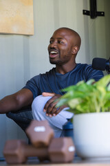 Adult African man laughing and speaking into microphone on boom in small studio with plant © WavebreakMediaMicro