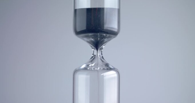 Close up shot of modern design sand clock / hourglass on a grey background.