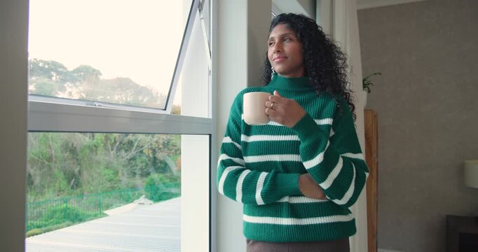 African American woman in green knit by casement window, camera moving in, sipping mug, reflecting