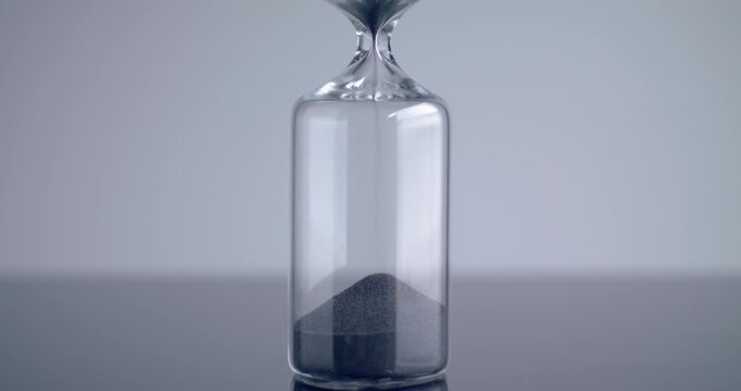 Close up shot of modern design sand clock / hourglass on a grey background.