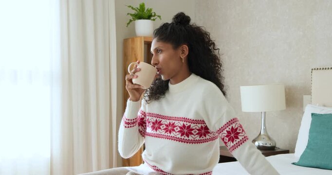 African American woman sitting on bed in bedroom, sipping pale mug while sunlight drawing smile