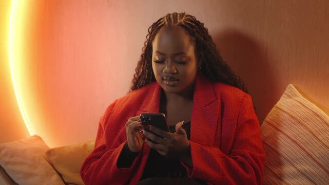 African American woman texts on phone and smiles, using mobile dating app