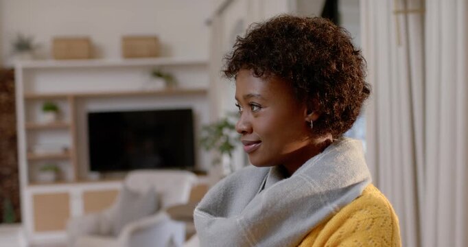 African woman standing home prompted off-cam turning to cam meeting gaze laughing scarf, copy space