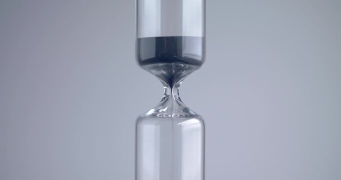 Close up shot of modern design sand clock / hourglass on a grey background.
