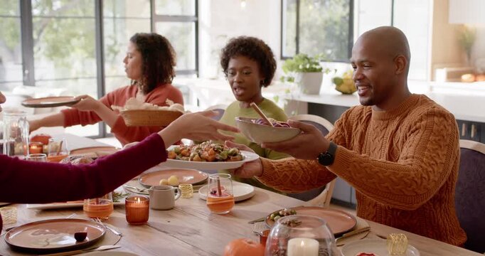 African American family in knits passing dishes as hands reaching across table sharing bread basket