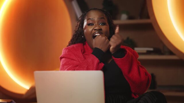 Black woman reads great news on laptop, celebrating successful business deal