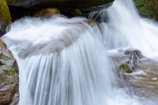 small waterfall closeup. beautiful cascade on the water stream with mossy rock