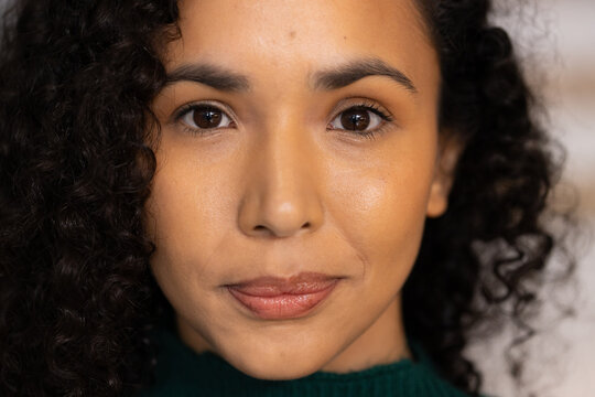 African American woman looking at camera in studio showing dark green ribbed sweater and curly hair