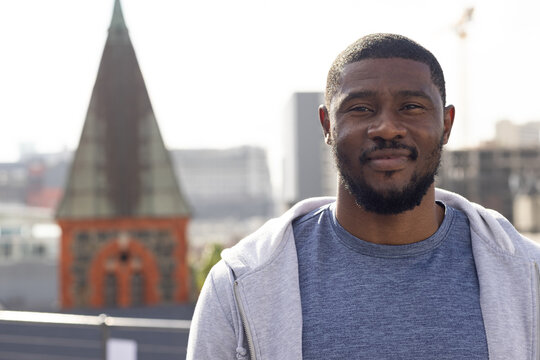 Man standing on roof wearing gray hoodie over blue tee, railing steeple crane, copy space