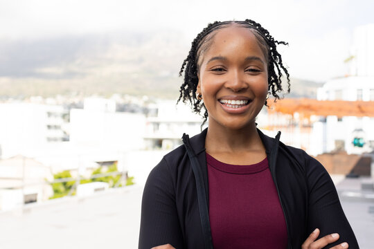 African American woman standing on rooftop terrace, wearing maroon top and black jacket, copy space