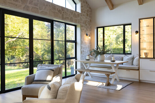 Built-in banquette is anchoring trestle table in sunlit dining nook with potted centerpiece