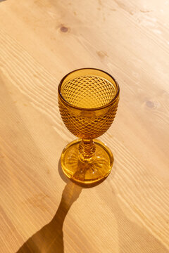 amber gold vintage goblet on light wood table with afternoon shadow