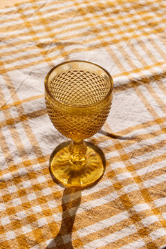 amber gold vintage goblet on handmade patterned linen napkin with afternoon shadow