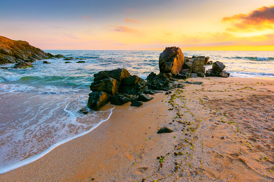 sea beach at sunrise. Bulgaria summer vacation background. colorful sky with glowing clouds. waves, sand and rocks in morning light