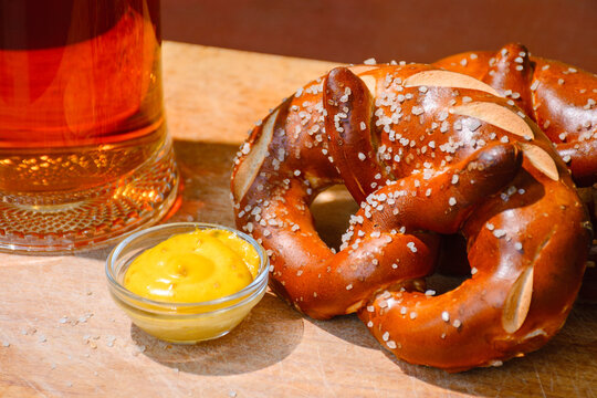 beer pretzel and mustard on a wooden table. rustic oktoberfest drink and food background. grungy wall texture. closeup view