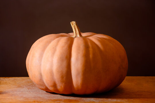orange pumpkin on the wooden table. autumn vegetable harvest. dark background for thanksgiving