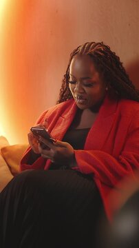 Smiling African woman scrolls through social media app on phone, digital life