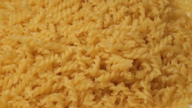 Uncooked fusilli pasta rotating on white background