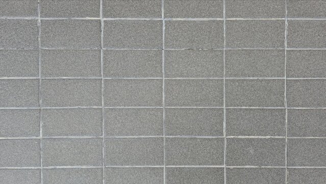 Grey concrete block flooring texture background grid pattern. Top view of a grey cinder block paving floor with uniform rectangular tiles for outdoor walkway design.