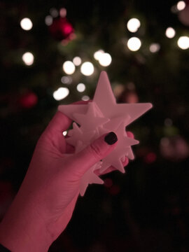 Mano sosteniendo estrella brillante frente a luces de Navidad