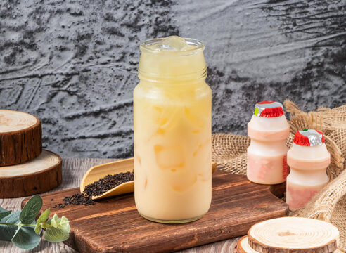 Iced Yakult Green Tea in a glass jar with probiotic yogurt drinks on a wooden board.