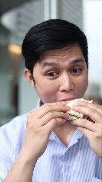 asian employee man having brunch sandwich in the office while relaxing for people lifestyle concept