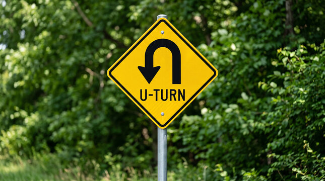 Yellow U-Turn Traffic Sign on Metal Post Against Lush Green Forest Background
