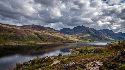 Naklejka premium Dramatic moody clouds over scenic Scottish lake and mountain landscape in summer