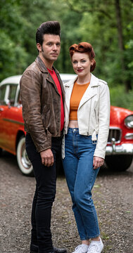 Vintage 1950s rock and roll couple posing near retro classic car outdoors