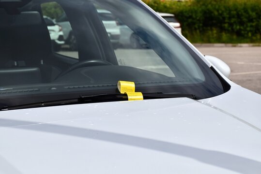 A yellow fine ticket under the car wiper. Parking fine notice. The vehicle is parked in the wrong place or the parking time has expired.