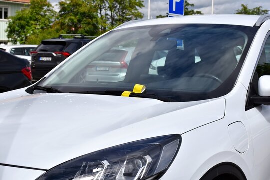 A yellow fine ticket under the car wiper. Parking fine notice. The vehicle is parked in the wrong place or the parking time has expired.