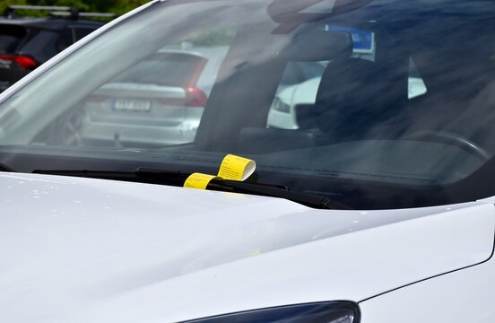 A yellow fine ticket under the car wiper. Parking fine notice. The vehicle is parked in the wrong place or the parking time has expired.