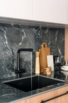 Modern kitchen interior with black faucet and green marble countertop