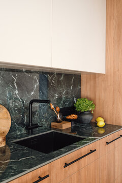 Modern kitchen with green marble countertop and black faucet above the sink