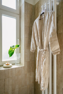 Modern bathroom with a shower head and a robe hanging in the morning light